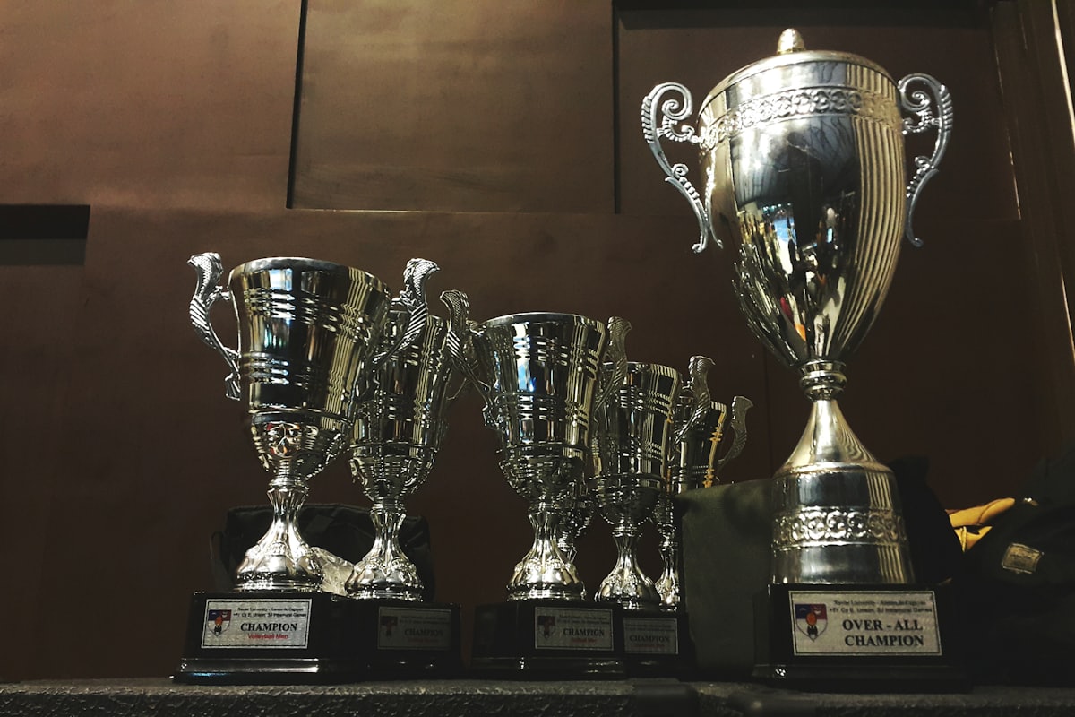 Deretan piala perak dan emas di atas meja — ilustrasi turnamen slot